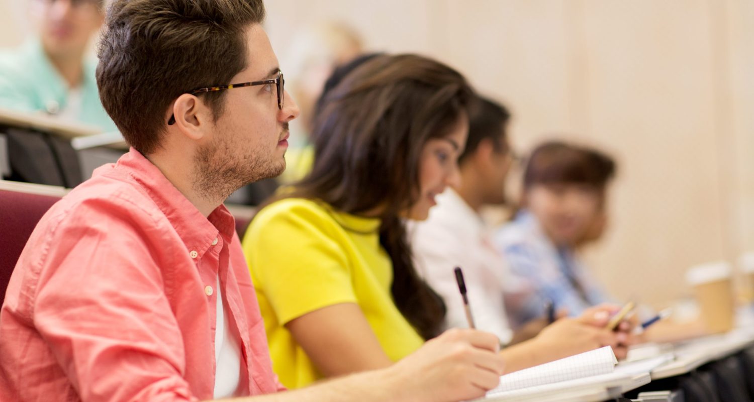 group of students with notebooks in lecture hall education, high school, university, learning and people concept - group of international students with notebooks writing in lecture hall and talking