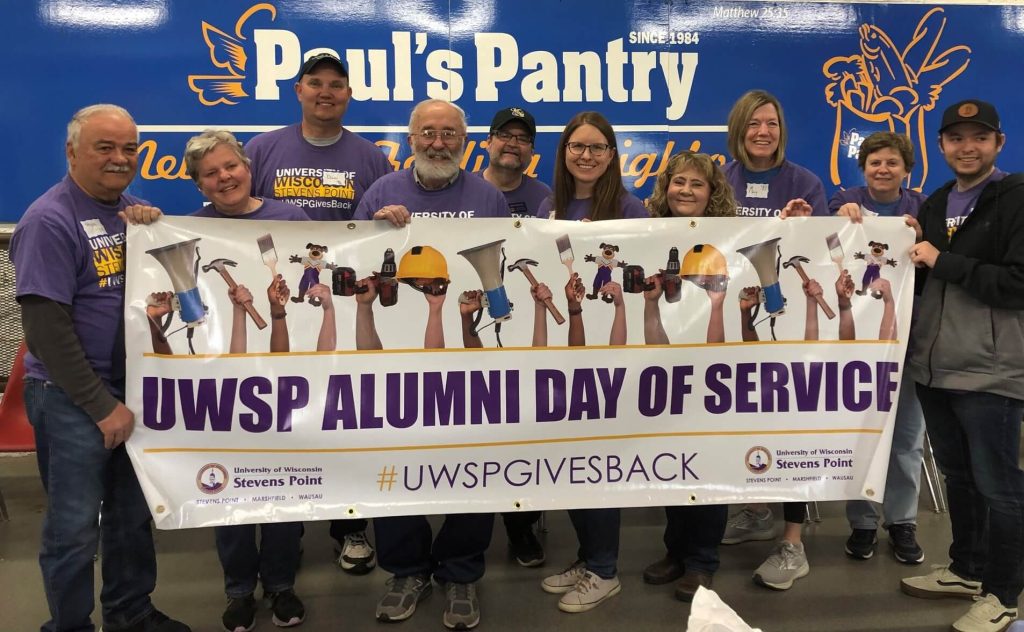 UWSP Alumni and volunteers at Paul's Pantry holding a banner that reads UWSP Alumni Day of Service