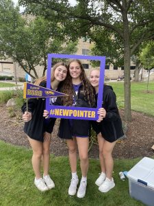 Three women in a photo frame prop that reads I'm a pointer