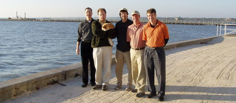 Rick Stuck ’82 poses with friends next to the ocean.