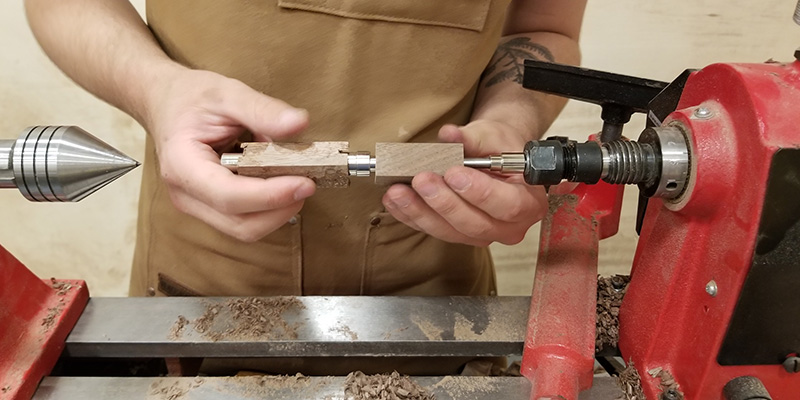 A close up of someone using a lathe to create a pen.