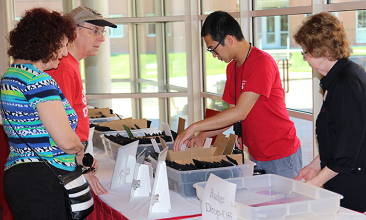 Alumni chat with a student worker as they get checked into Reunion.
