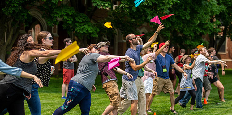 Alumni throw paper airplanes on Mac Field.