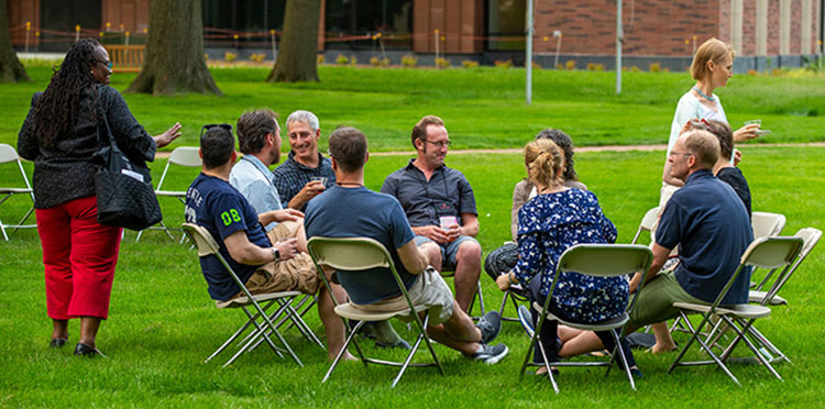 A group of alumni sit in a circle catching up.