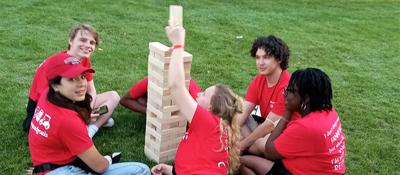 Six student staff members sit around a tower of Giant Jenga.