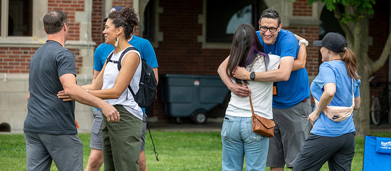 Alumni greet each other with smiles and hugs.