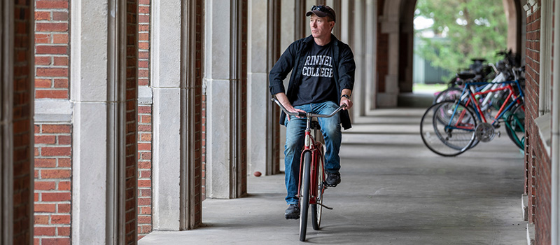An alumnus rides through the loggia on the campus of Grinnell College.