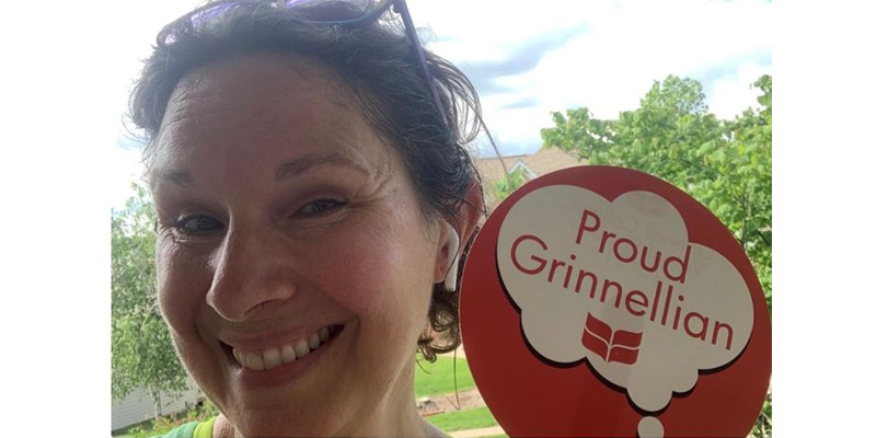 Robin Kopelman ‘95 holds up a sign that says "Proud Grinnellian"