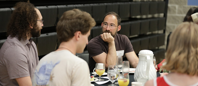 Caleb Elfenbein, associate professor of history and religious studies, chats with class of 2020 graduates during Pancakes and Professors.