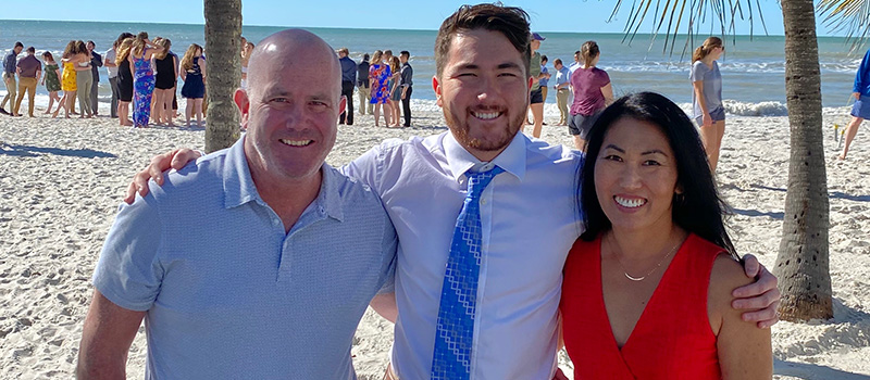 Tom Hopkins, left, Sean Hopkins ’22, and Sandy Kaneoka posed for a picture on the beach of Naples, FL.