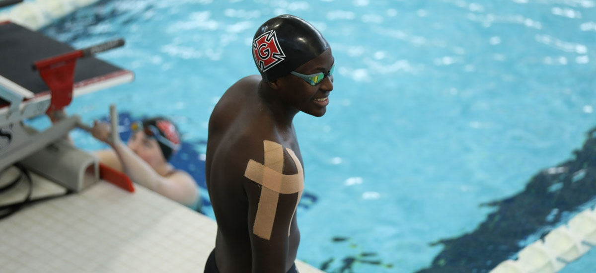 John Kafumbe ’28 in a swim cap and goggles on this side of a competition swimming pool.