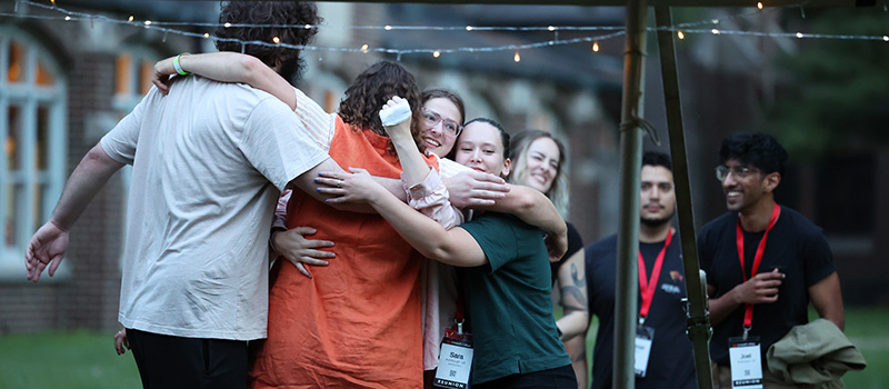 Alums from the 5th reunion cluster take part in a group hug at a welcome event Thursday outside James Hall.