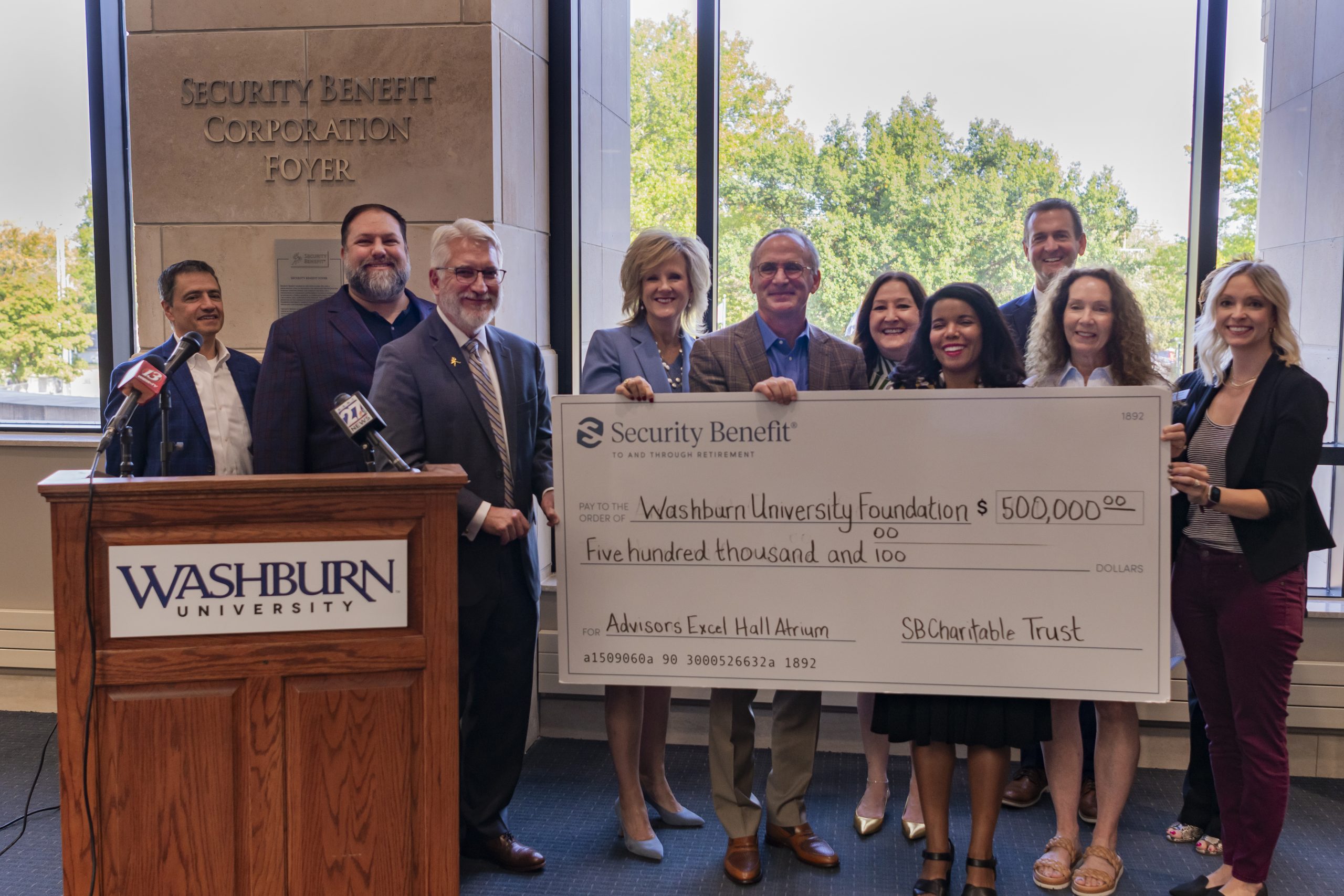 A group of people standing behind a check from Security Benefit made out to Washburn University Alumni Association and Foundation for $500,000